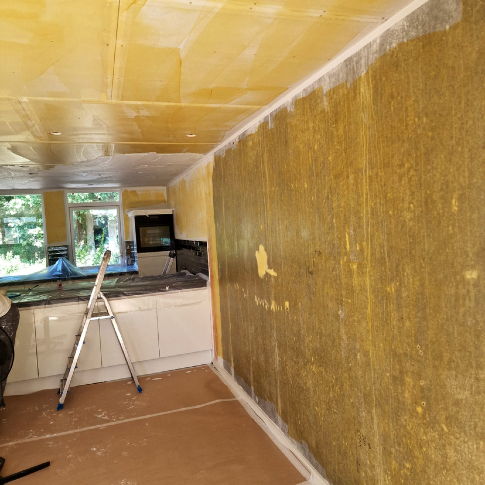 Keukenwand tijdens de voorbereiding voor stucwerk, vloer afgedekt en trap in de ruimte
